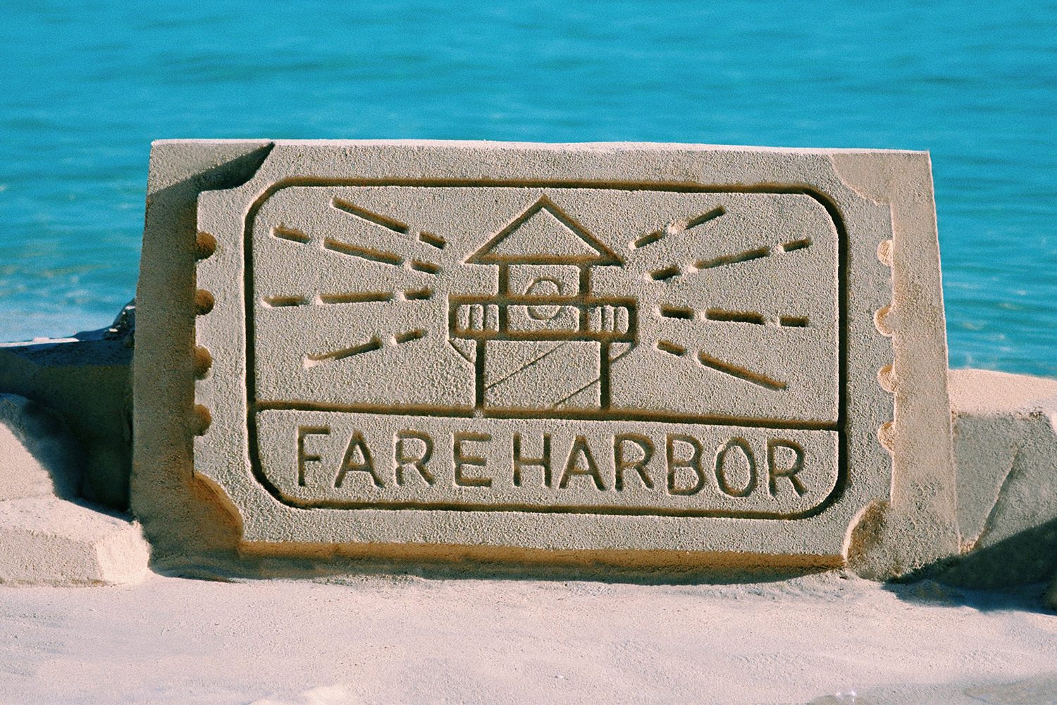 A sand sculpture of the FareHarbor logo